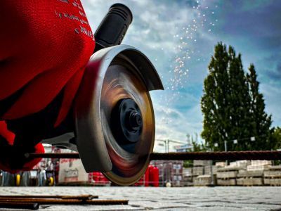 Winkelschleifer schneidet Metall, Funken fliegen, zeigt Werkzeugnutzung im Bauhandwerk im Freien.